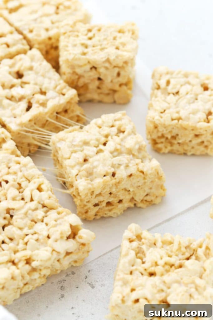 Gluten-Free M and M Rice Krispies Treats 10 Pulling a square of gluten-free brown butter rice krispies treats away, revealing its gooey and chewy texture.