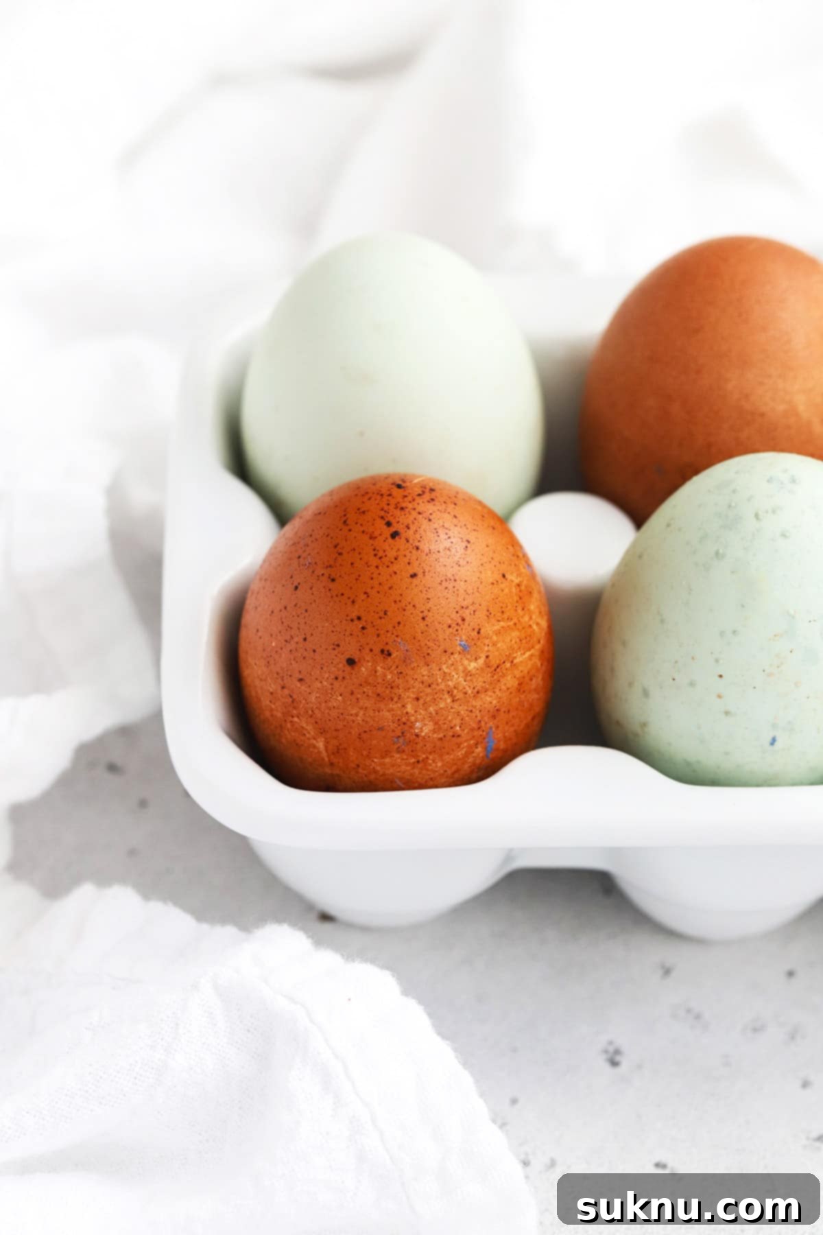 A collection of colorful farm eggs in a white egg carton, highlighting the ingredient this guide helps you avoid.