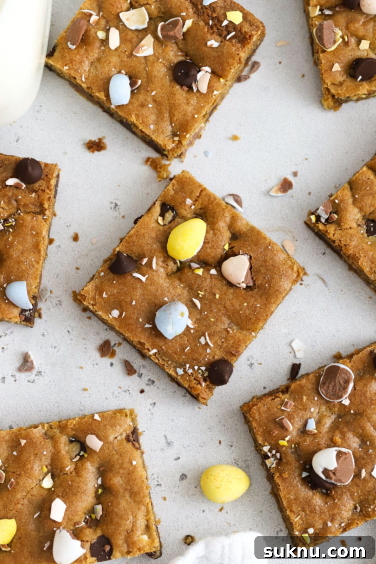 Decadent Gluten-Free Cadbury Blondies 5 Perfectly cut squares of gluten-free Cadbury egg blondies, showing off their chewy texture and colorful mini egg inclusions, arranged invitingly on a white surface.