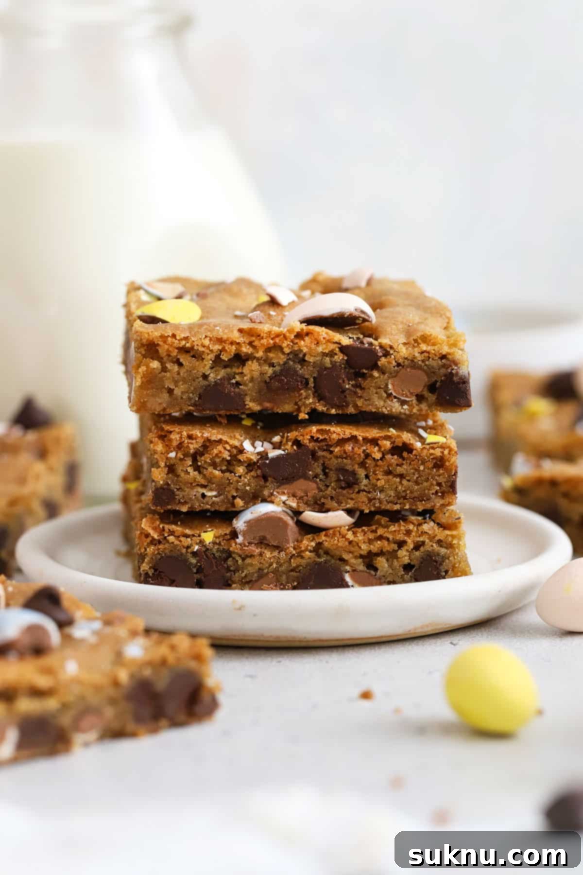 Decadent Gluten-Free Cadbury Blondies 6 Stack of three gluten-free Cadbury cookie bars on a pristine white plate, showcasing the vibrant colors of the mini eggs and the inviting chewiness of the blondies.