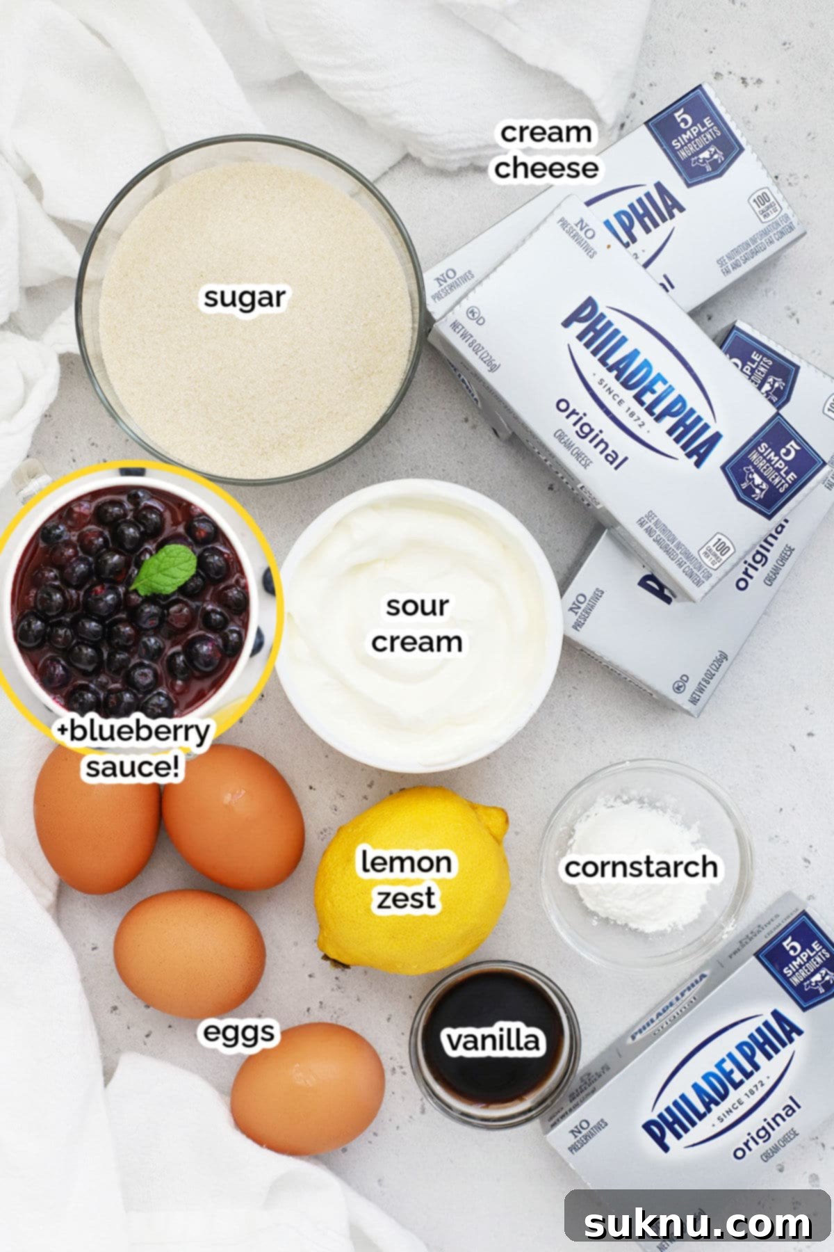 Luscious Gluten-Free Blueberry Cheesecake 3 A selection of fresh ingredients laid out, including gluten-free graham crackers, cream cheese blocks, fresh blueberries, lemons, and butter, ready for making blueberry cheesecake.