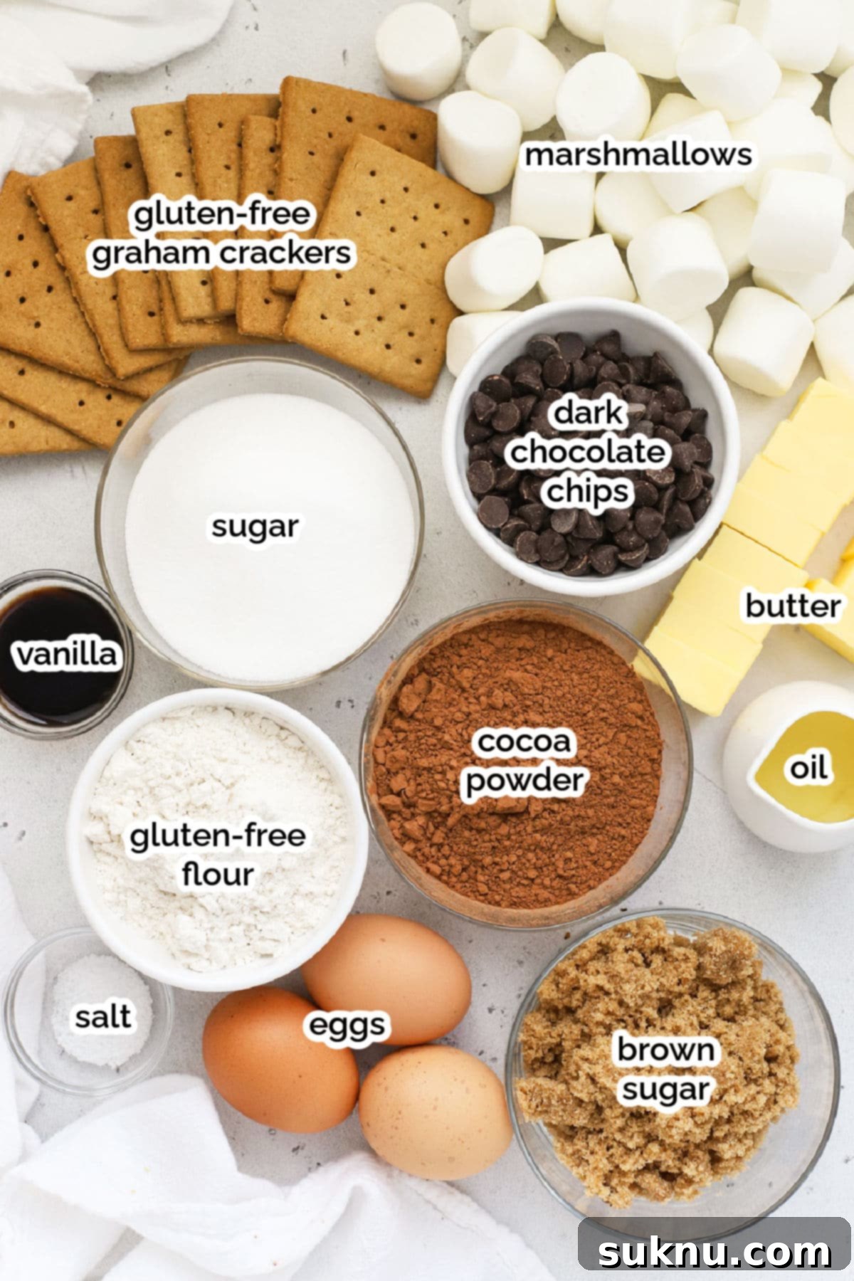 Decadent Gluten-Free S'mores Brownies 3 A collection of ingredients laid out for making gluten-free s'mores brownies, including chocolate, butter, eggs, flour, marshmallows, and graham crackers.