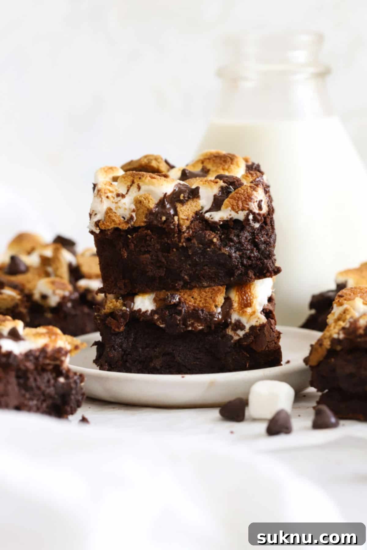 Decadent Gluten-Free S'mores Brownies 8 Stack of three gluten-free s'mores brownies on a white dessert plate, with gooey marshmallow and chocolate evident.