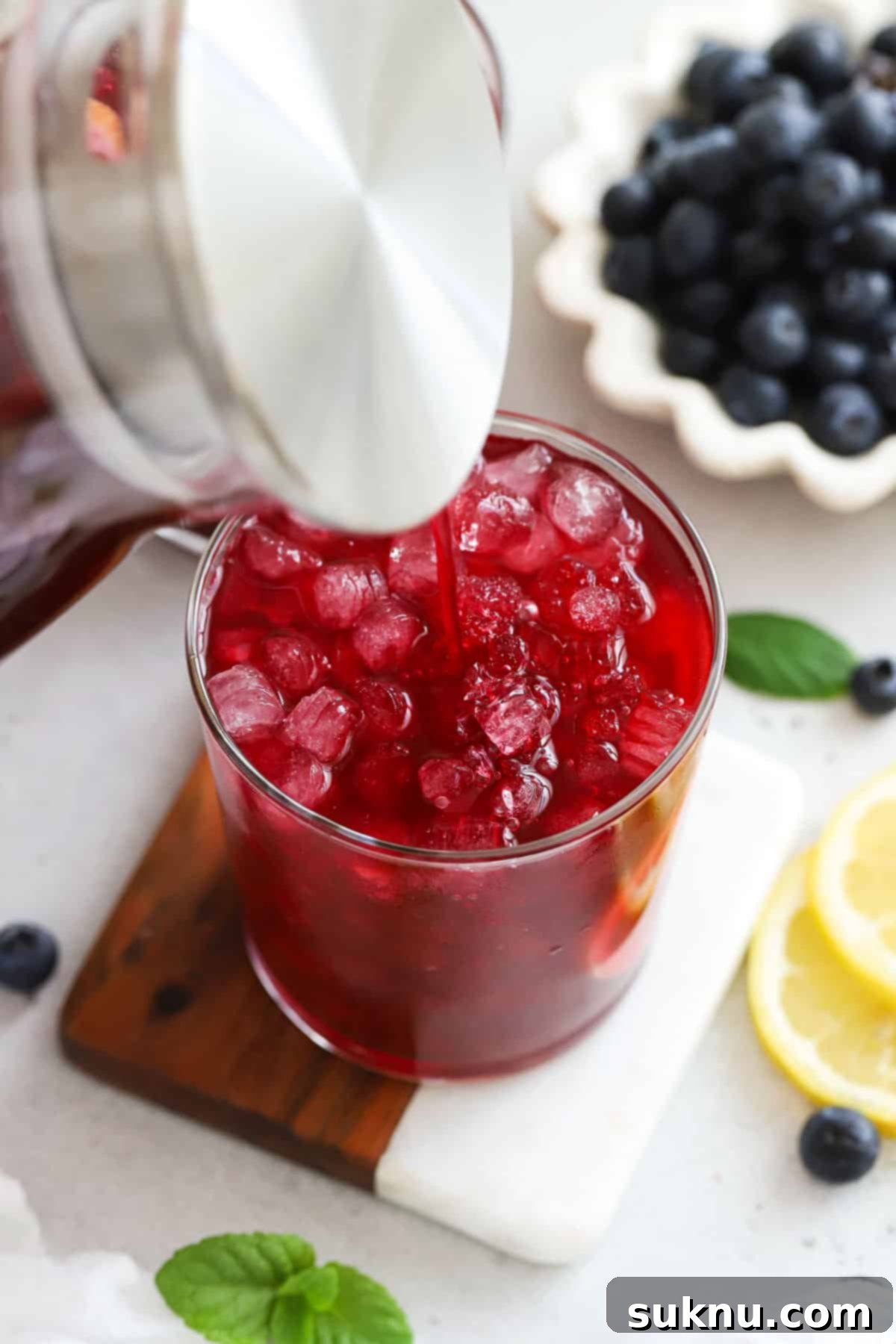 pouring blueberry lemonade into a glass