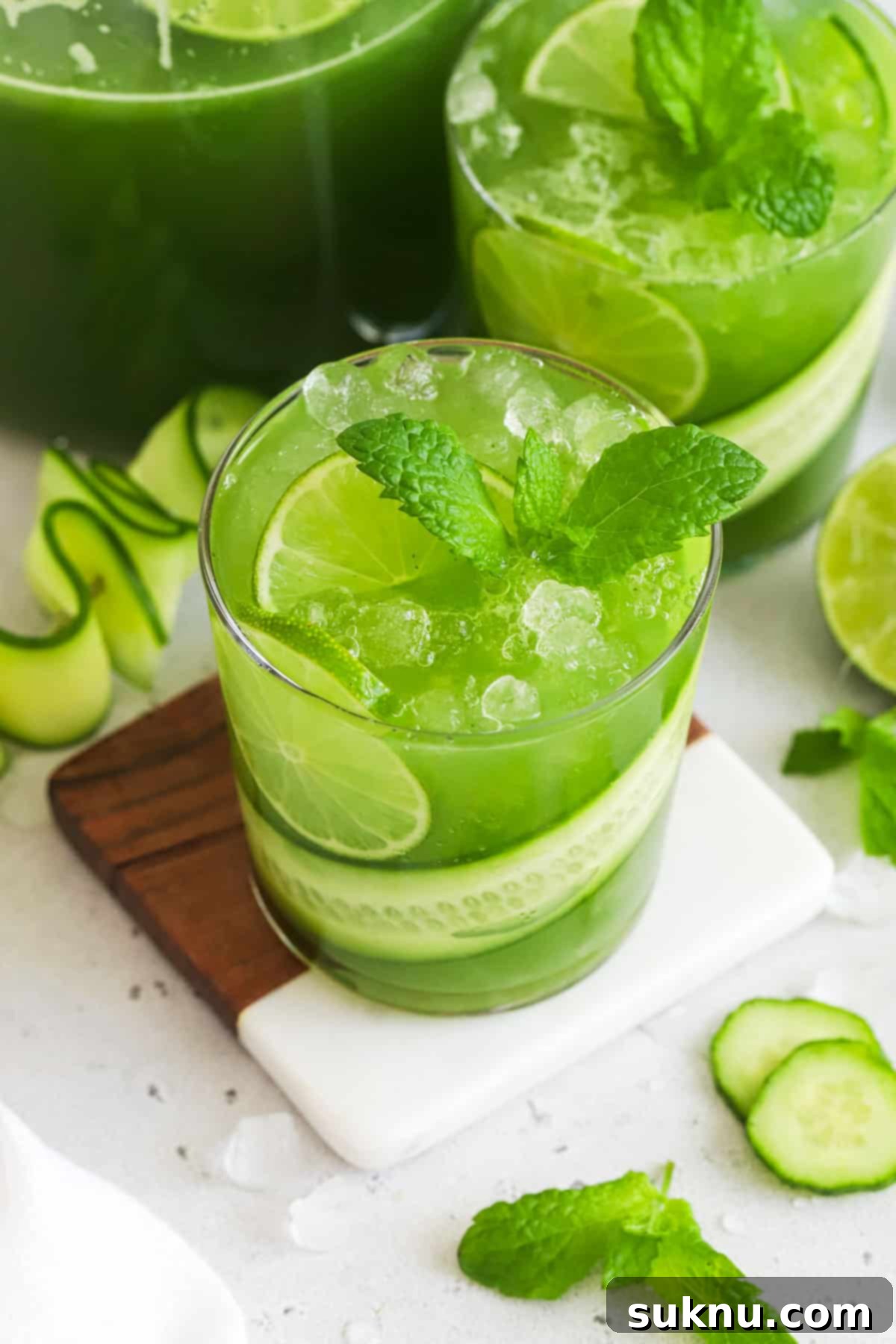 Crisp Cucumber Refreshment 2 Cucumber Mint Cooler garnished with a cucumber ribbon, fresh mint, and lime