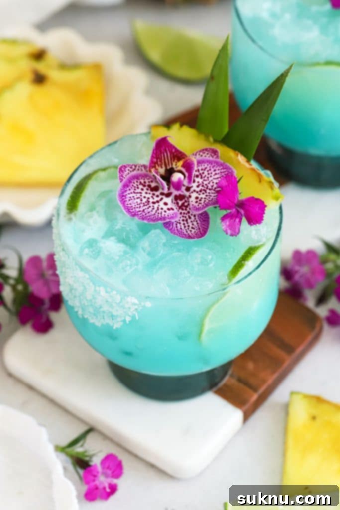 Crisp Cucumber Refreshment 8 Virgin Blue Hawaiian drink topped with purple flowers and fresh pineapple