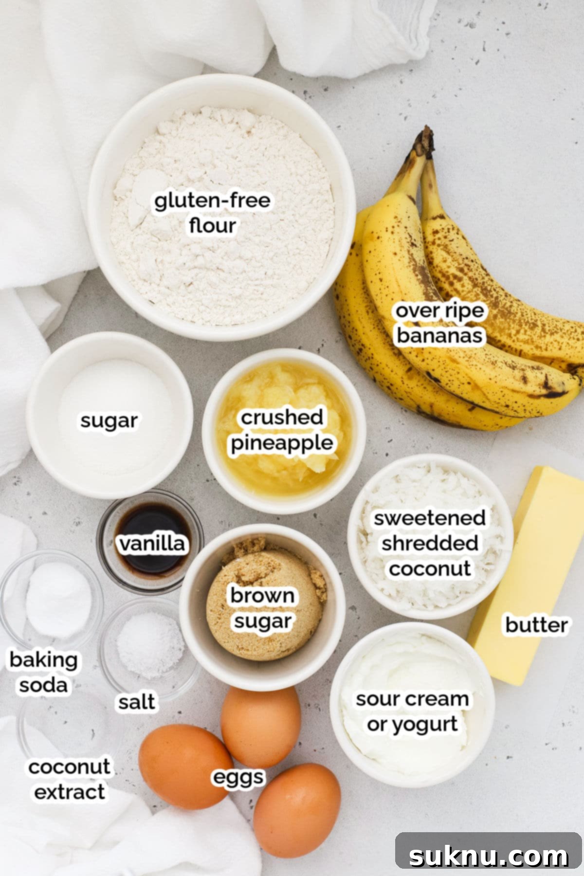 A flat lay photograph showcasing all the ingredients required for making gluten-free pineapple coconut banana bread, neatly arranged on a rustic surface.