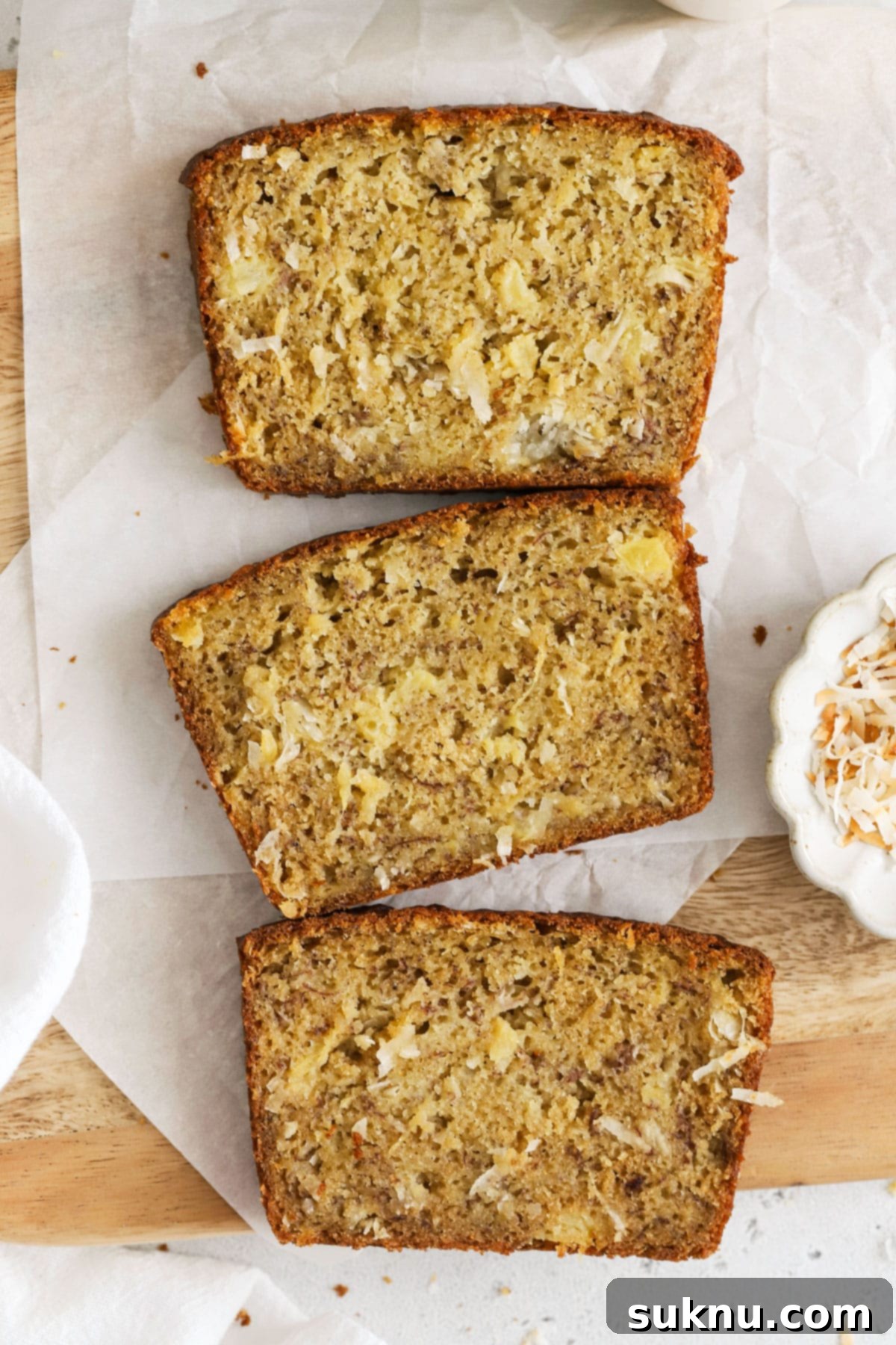 Thick slices of gluten-free pineapple coconut banana bread arranged on a wooden cutting board, ready to be enjoyed.