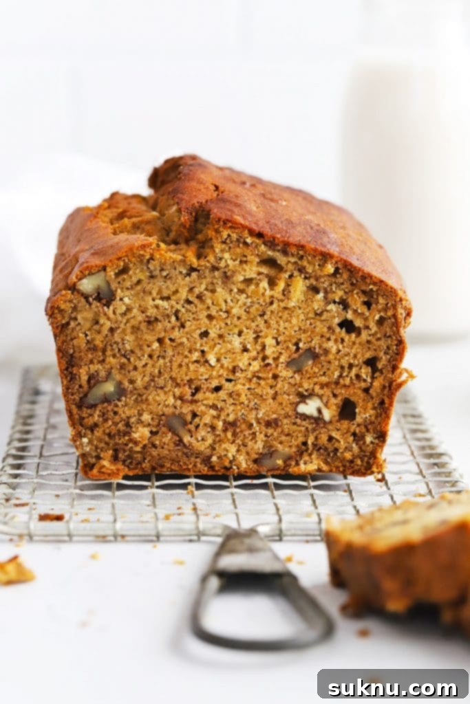 A front view of gluten-free brown butter banana bread being sliced, revealing its tender crumb.