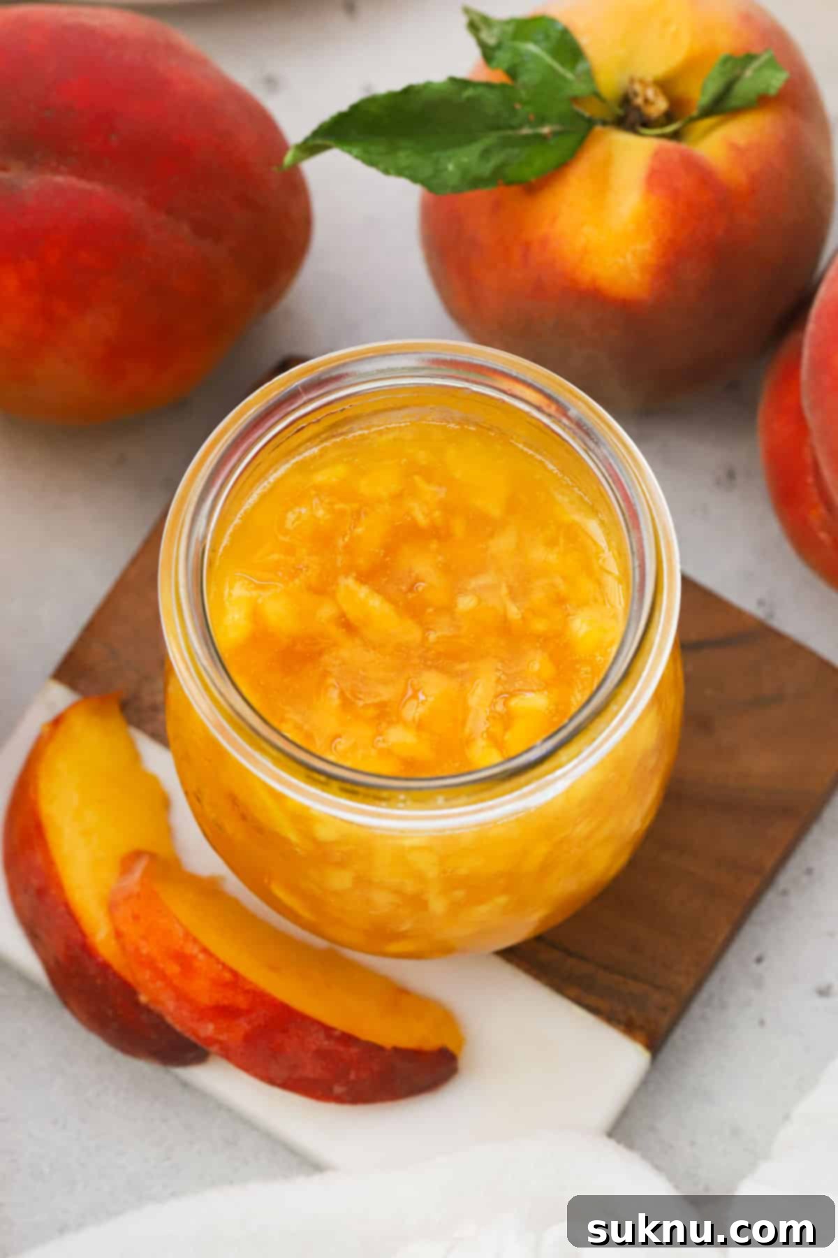Effortless Low Sugar Peach Freezer Jam 11 a jar of peach freezer jam next to fresh peaches