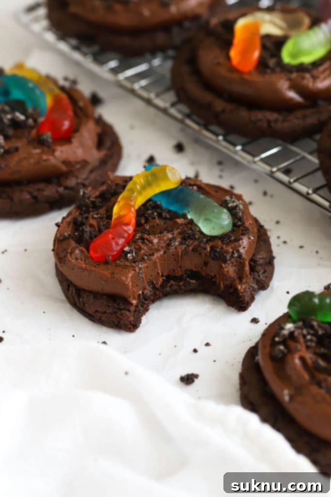 gluten-free dirt cake cookies topped with chocolate frosting, gluten-free Oreo cookie crumbs and gummy worms