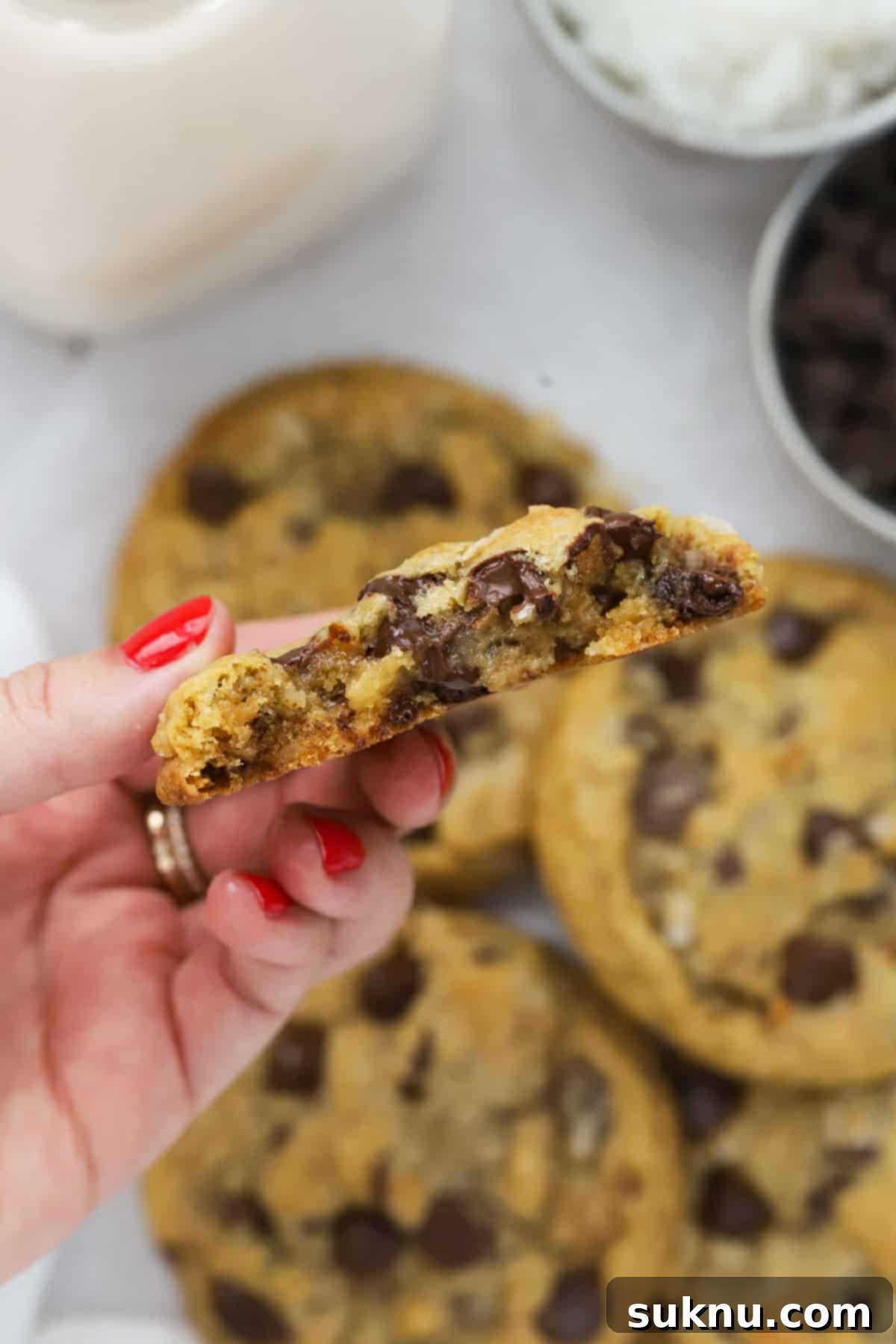 A gluten-free coconut chocolate chip cookie broken in half to reveal its soft, chewy center filled with chocolate and coconut.