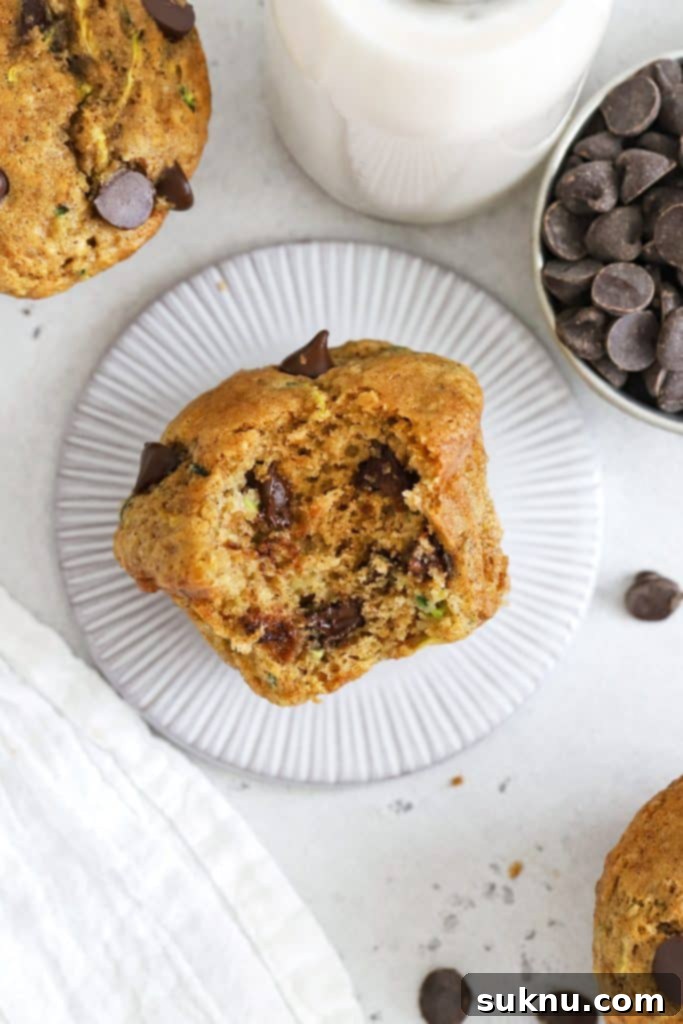 Overhead view of a gluten-free chocolate chip zucchini muffin with a bite out of it, revealing how moist and fluffy it is inside