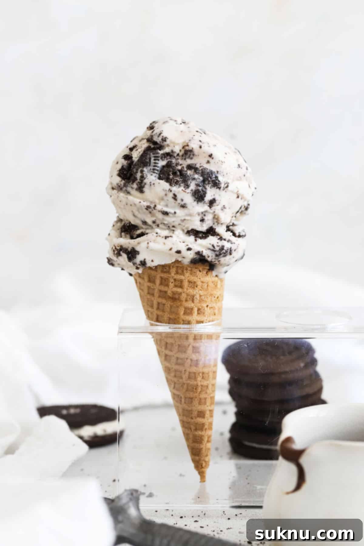 Homemade gluten-free cookies and cream ice cream in a cone, drizzled with chocolate sauce