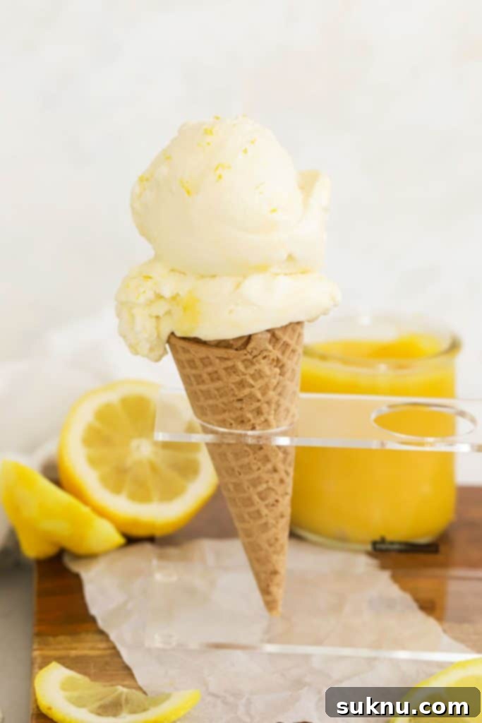 A scoop of lemon curd ice cream on a gluten-free waffle cone