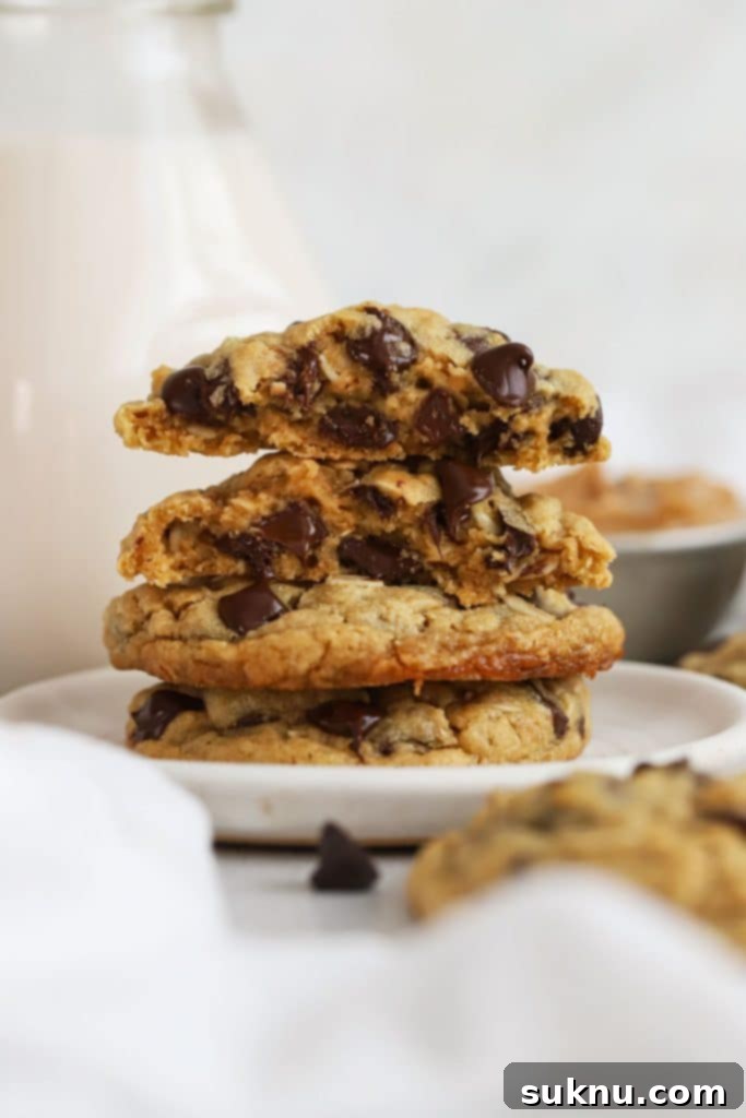 Comforting Gluten-Free Cinnamon White Chocolate Oatmeal Delights 12 gluten-free peanut butter oatmeal cookies stacked on a white dessert plate next to a bottle of milk