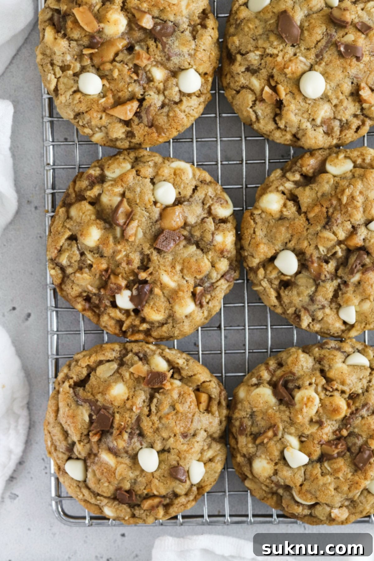Comforting Gluten-Free Cinnamon White Chocolate Oatmeal Delights 7 gluten-free oatmeal cookies with white chocolate chips and toffee bits, cooling on a wire rack