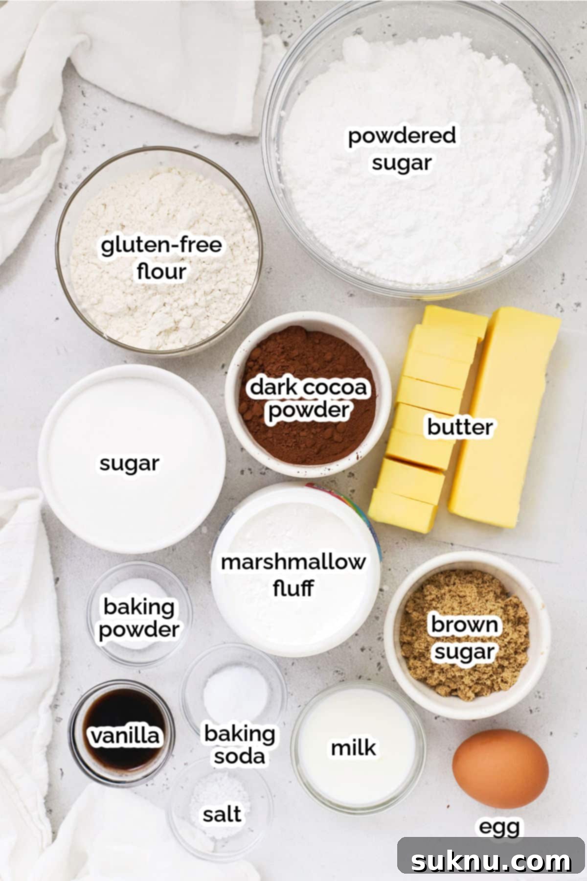 Ingredients for homemade gluten-free Oreos, including flour, cocoa powder, butter, sugar, and marshmallow fluff on a wooden board