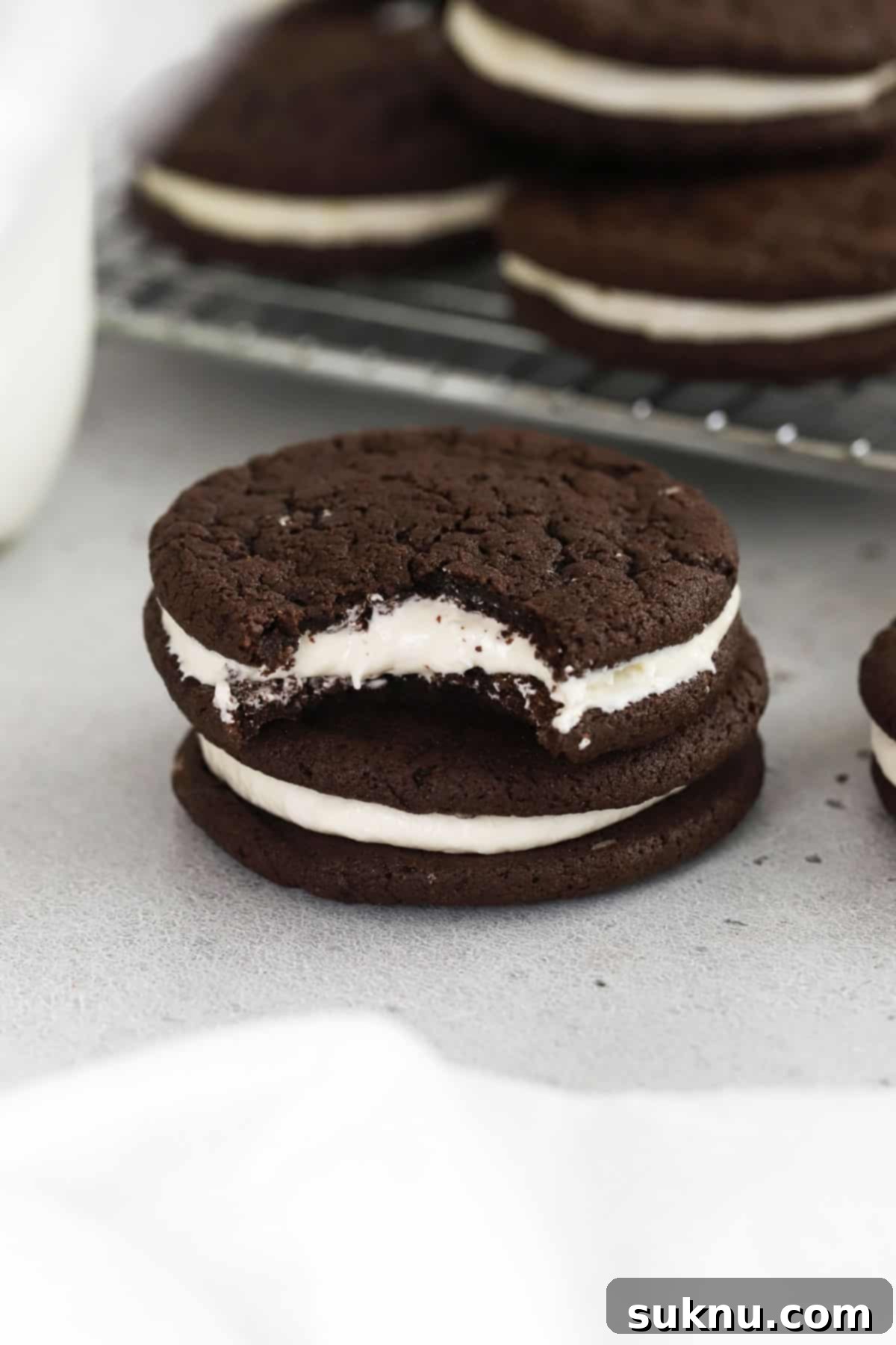 Two perfectly stacked gluten-free Oreo cookies alongside a charming bottle of milk