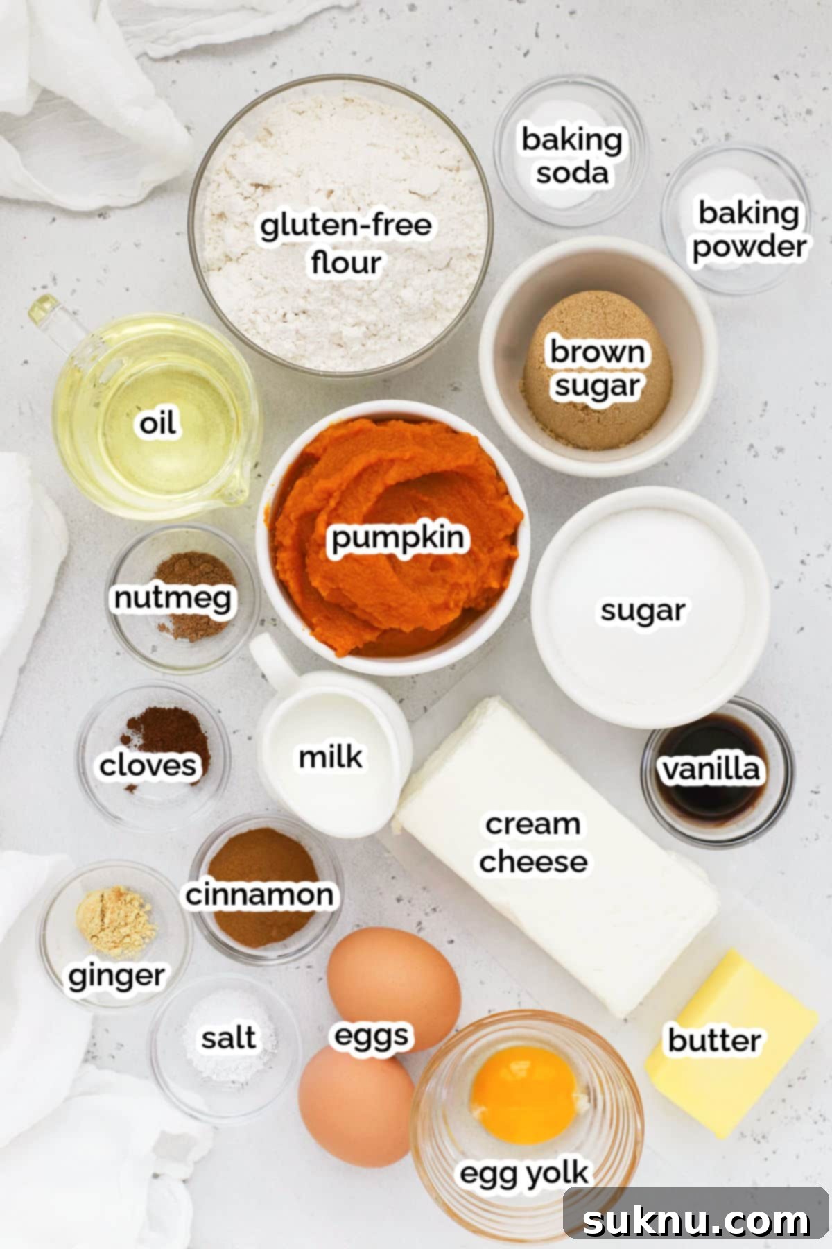 Spiced Gluten-Free Pumpkin Cream Cheese Muffins 4 Assorted ingredients for pumpkin cream cheese muffins laid out on a baking surface, including pumpkin puree, spices, flour, and cream cheese