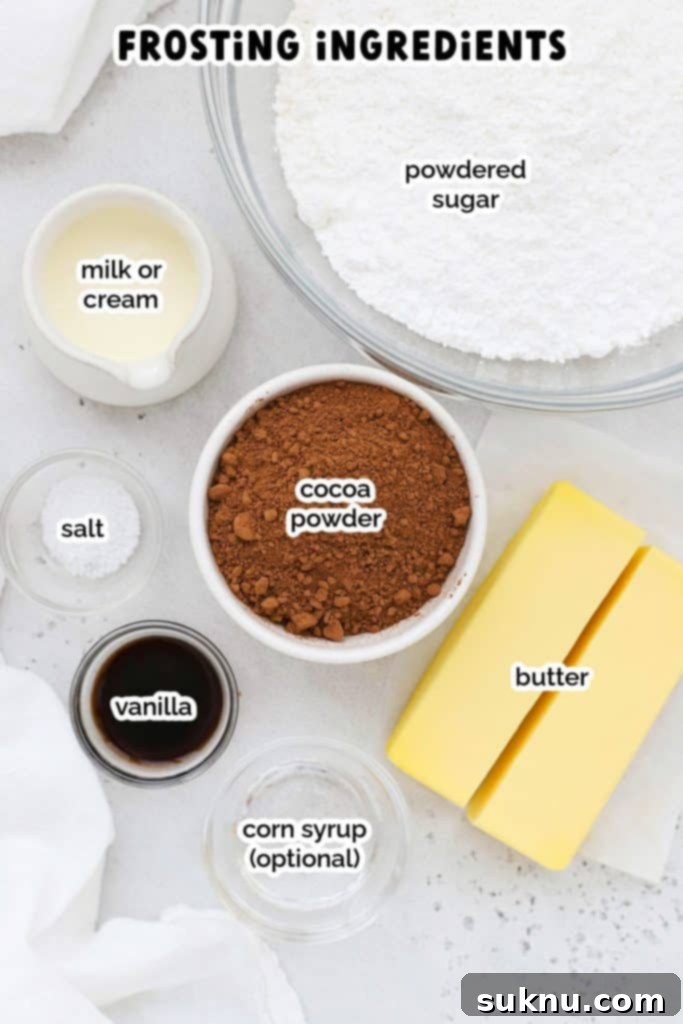A flat lay arrangement of ingredients required for making the luscious chocolate frosting: softened butter, powdered sugar, unsweetened cocoa powder, vanilla extract, a pinch of salt, and rich heavy cream.