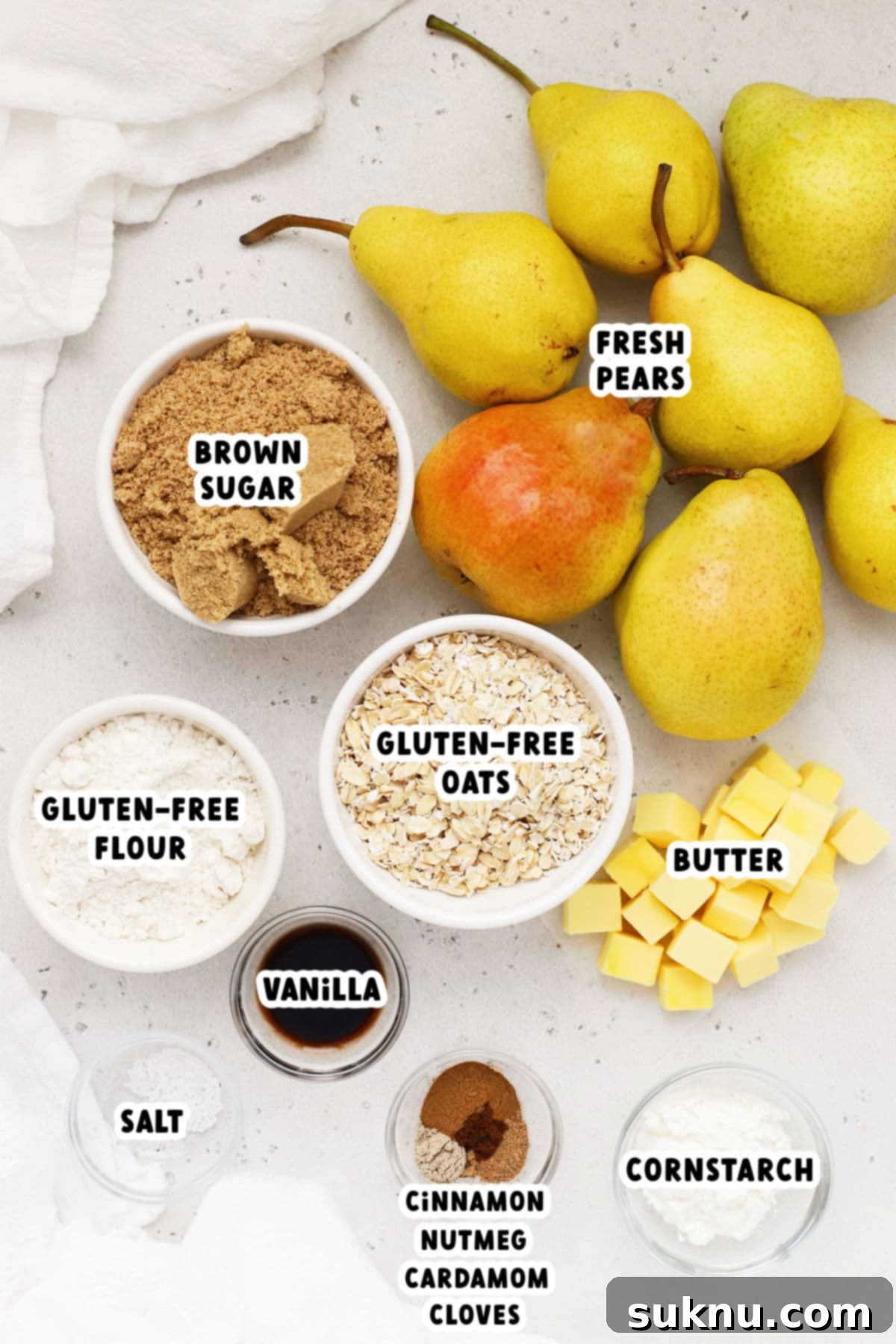 An organized display of ingredients for making gluten-free pear crisp, including fresh pears, brown sugar, a selection of warm spices, certified gluten-free oats, and gluten-free flour.
