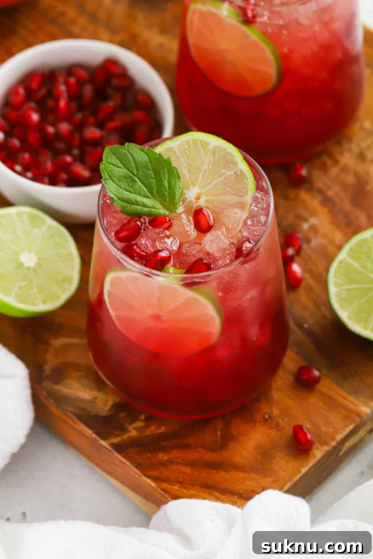 A dazzling red ginger pomegranate mocktail, beautifully garnished with fresh mint leaves and a slice of lime, exuding holiday cheer.