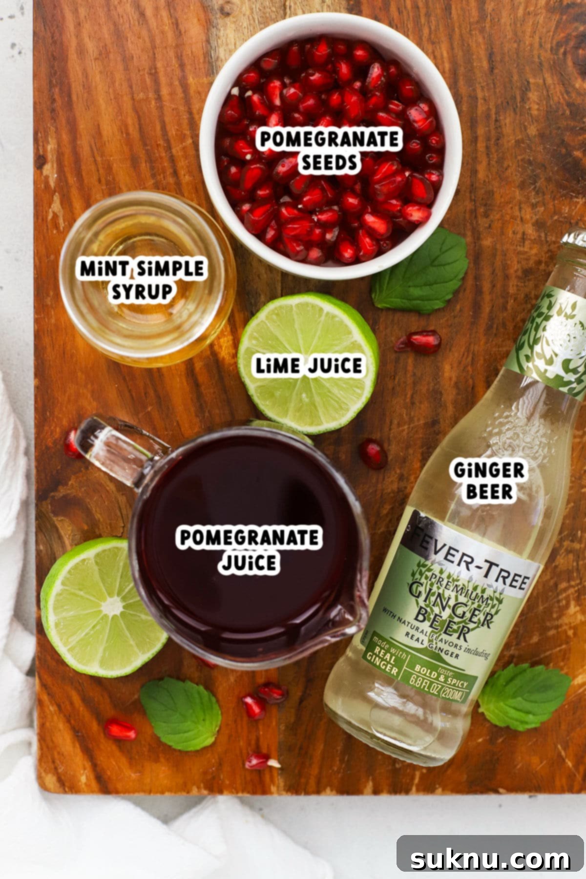 A vibrant display of fresh ingredients for the Ginger Pomegranate Mocktail, including luscious pomegranate juice, zesty limes, aromatic mint, and spicy ginger beer.