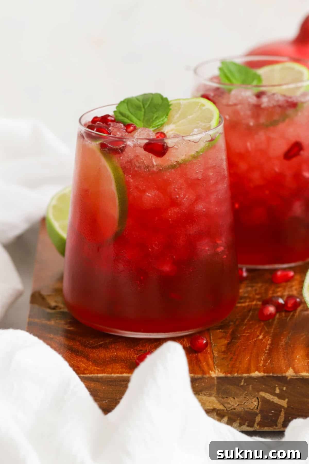 Multiple glasses of ginger pomegranate mocktails, garnished exquisitely with fresh mint and lime, arranged on a serving tray, perfect for a gathering.
