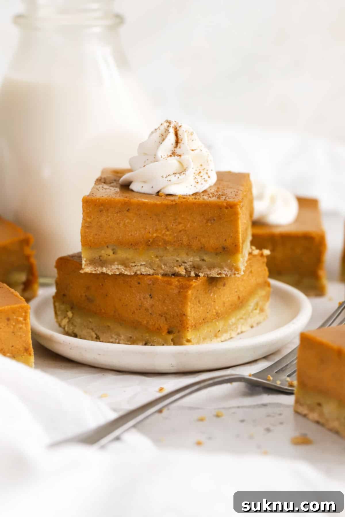 Gluten-free pumpkin pie bars stacked on a white dessert plate