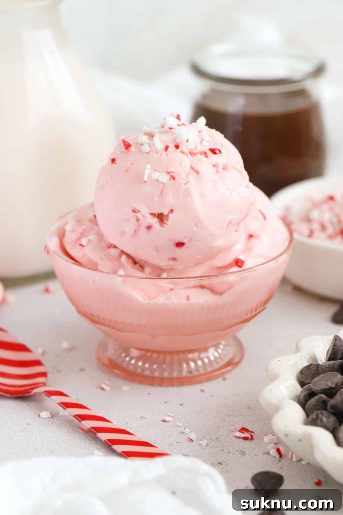 A pink dessert bowl with pink peppermint ice cream topped with candy cane bits