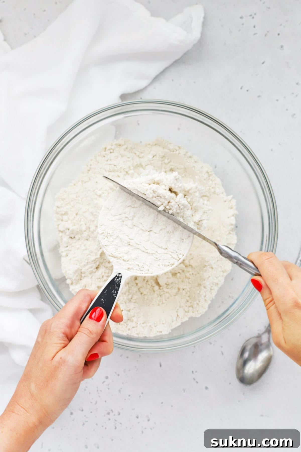 Master Flour Measurement For Perfect Baking 2 Overhead view of someone using the scoop and level method to measure flour correctly, emphasizing precise technique