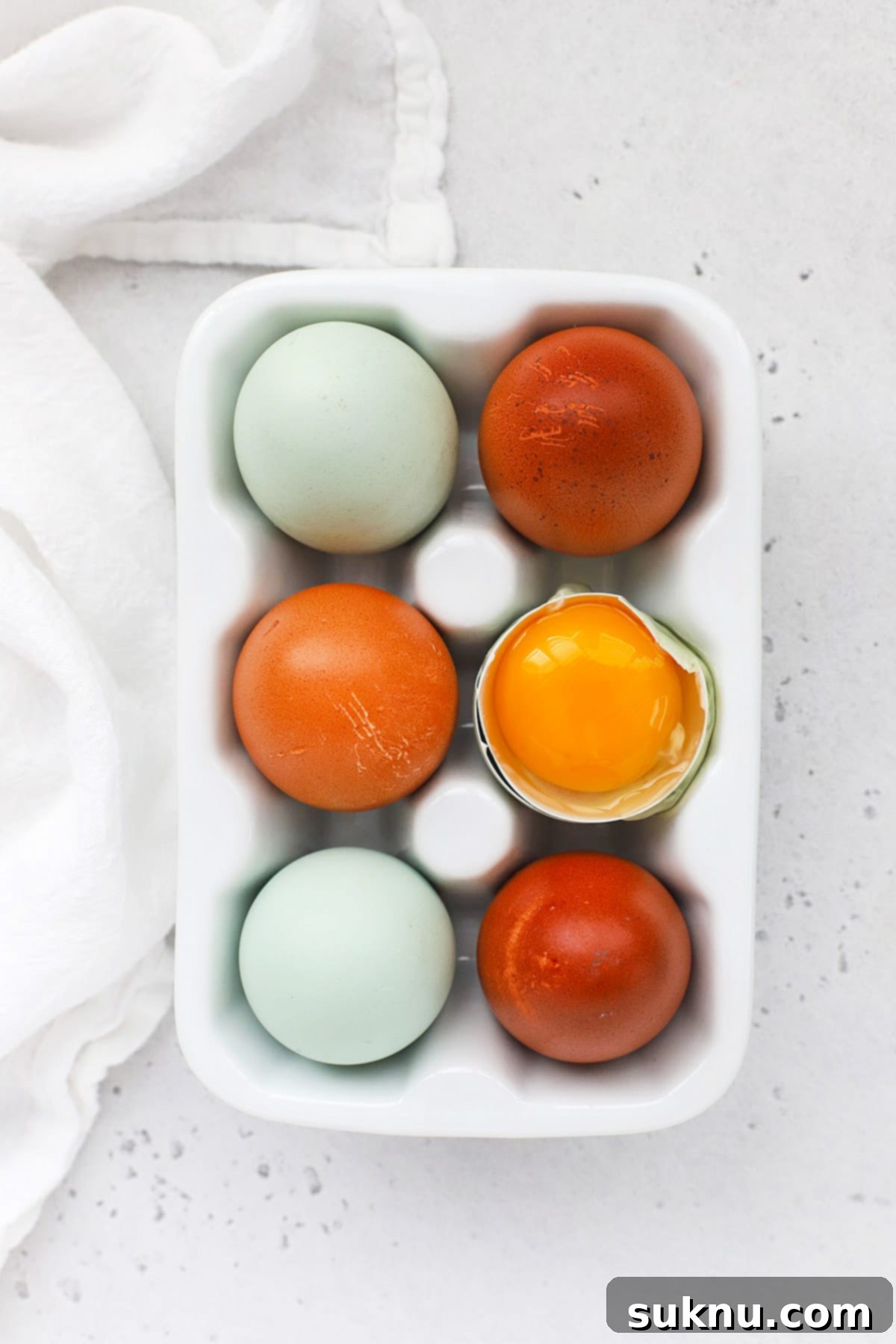 How to Separate Egg Whites and Yolks 2 Overhead view of an egg carton with 6 eggs, one egg is open revealing a golden yolk, symbolizing the start of egg separation