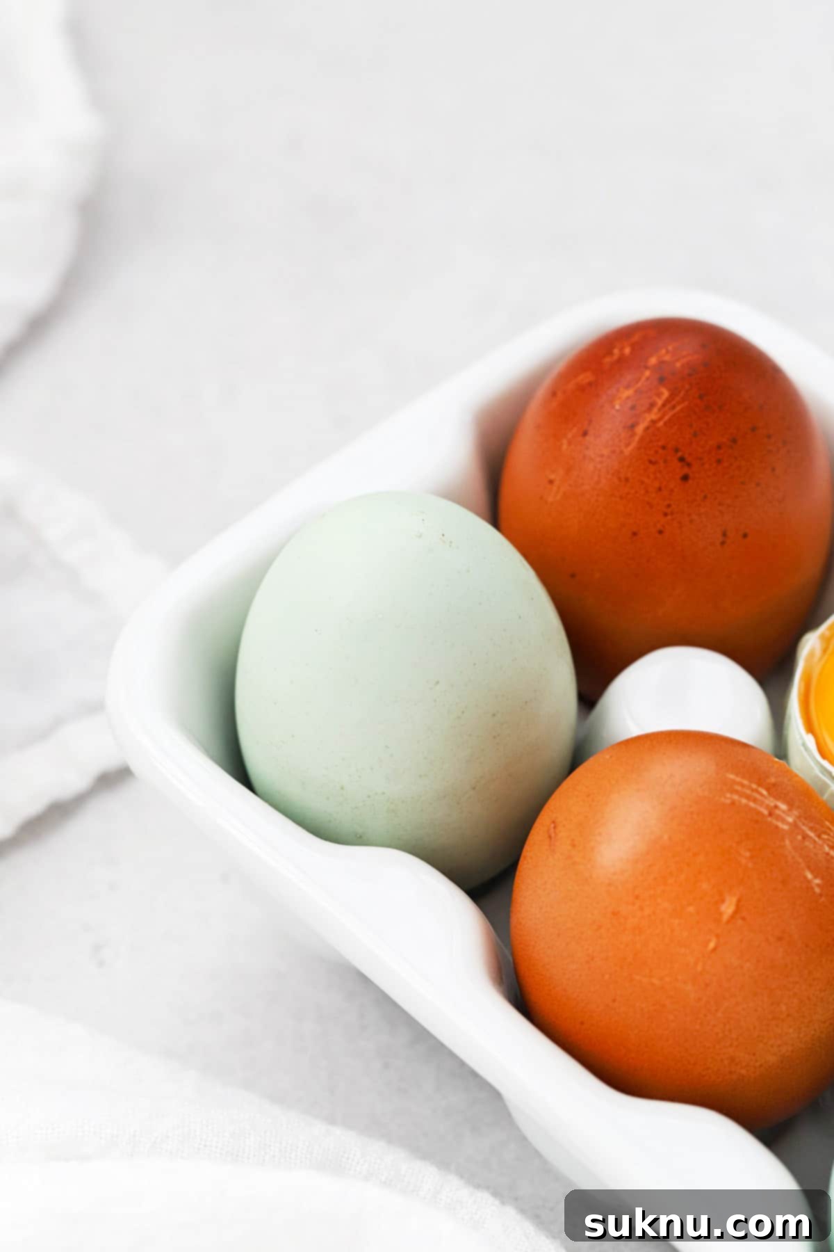 How to Separate Egg Whites and Yolks 11 Front view of an egg carton with 3 colorful eggs in view, representing fresh baking ingredients