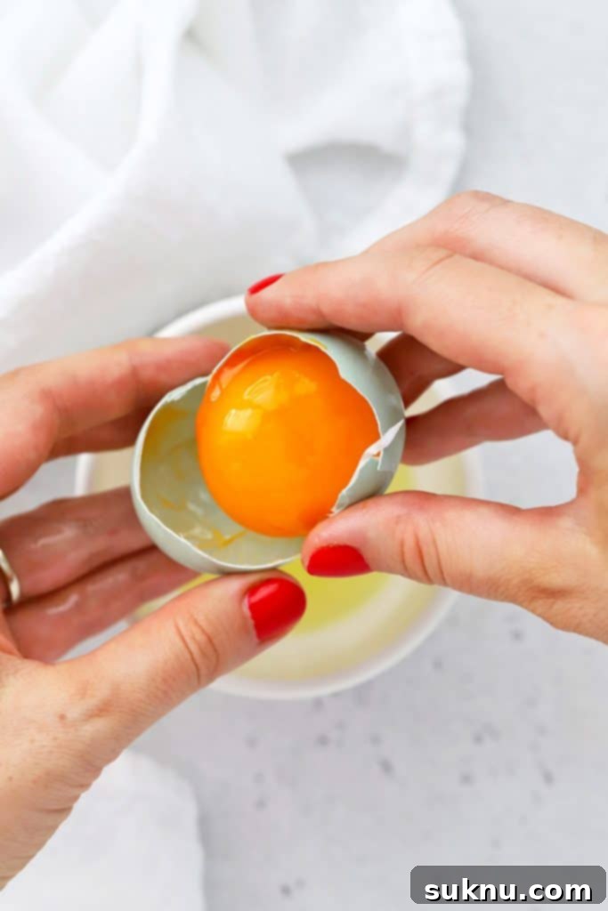 How to Separate Egg Whites and Yolks 6 Overhead view showing the traditional method of separating egg yolks and egg whites using egg shell halves