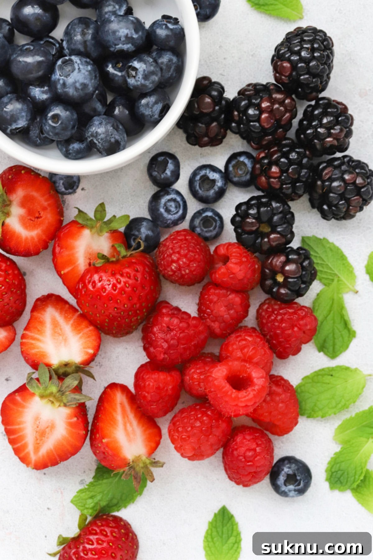 Overhead view of fresh berries and mint leaves for decorating gluten-free fruit pizza cookies