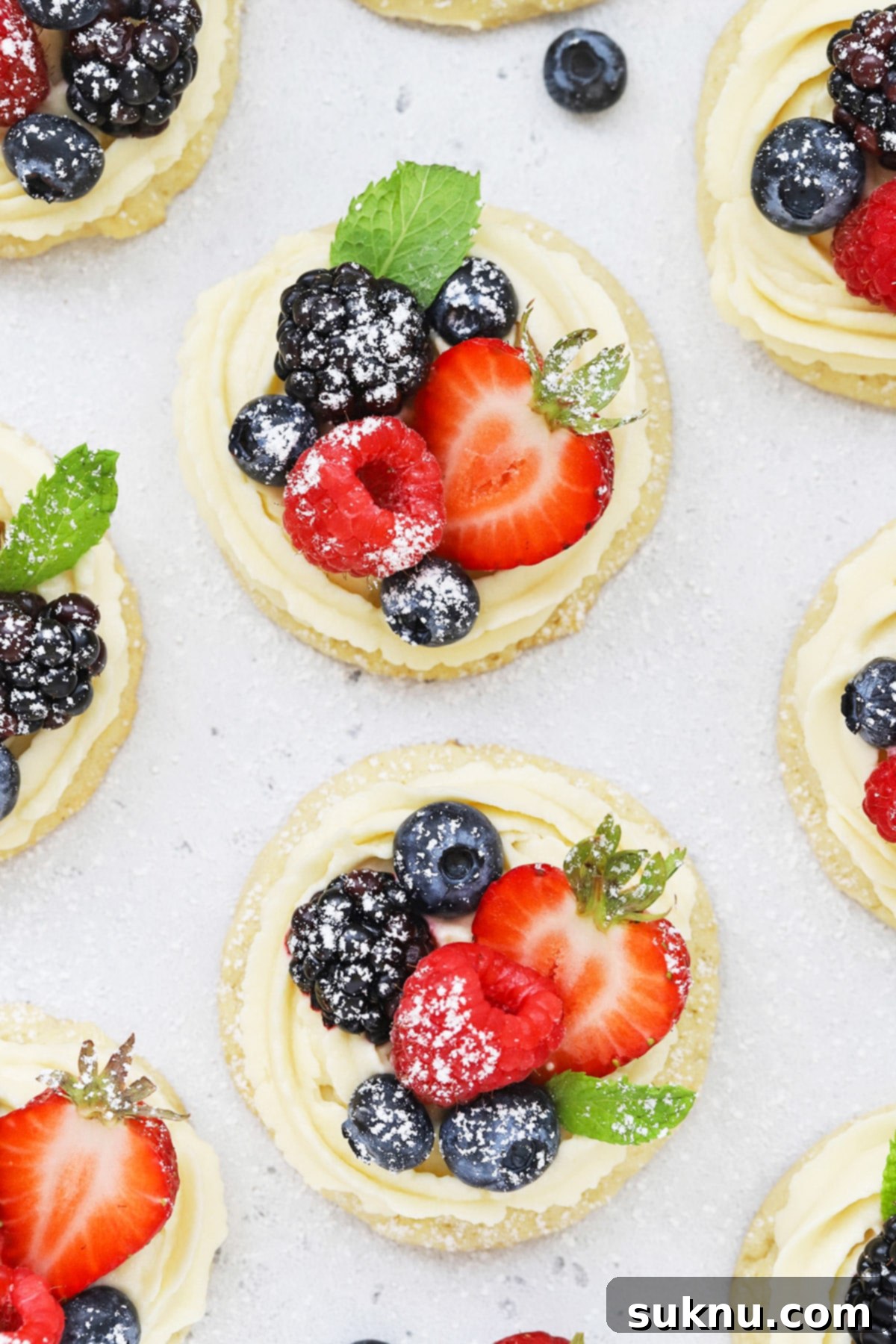 Overhead view of gluten-free fruit pizza cookies topped with cream cheese frosting berries and powdered sugar