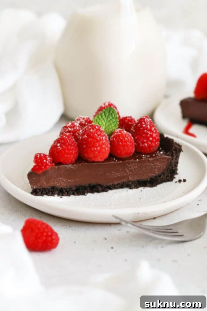 a slice of gluten-free chocolate ganache tart on a white plan