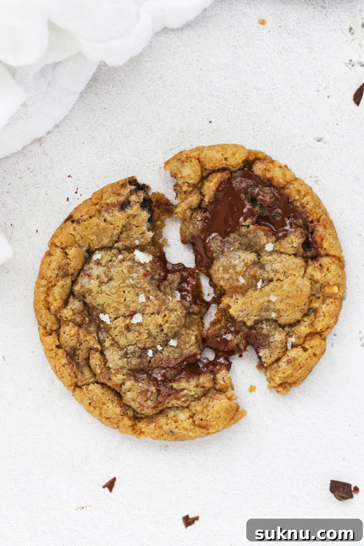 Overhead image of a gooey gluten-free brown butter toffee chocolate chip cookie being pulled apart, revealing its molten chocolate and toffee pieces