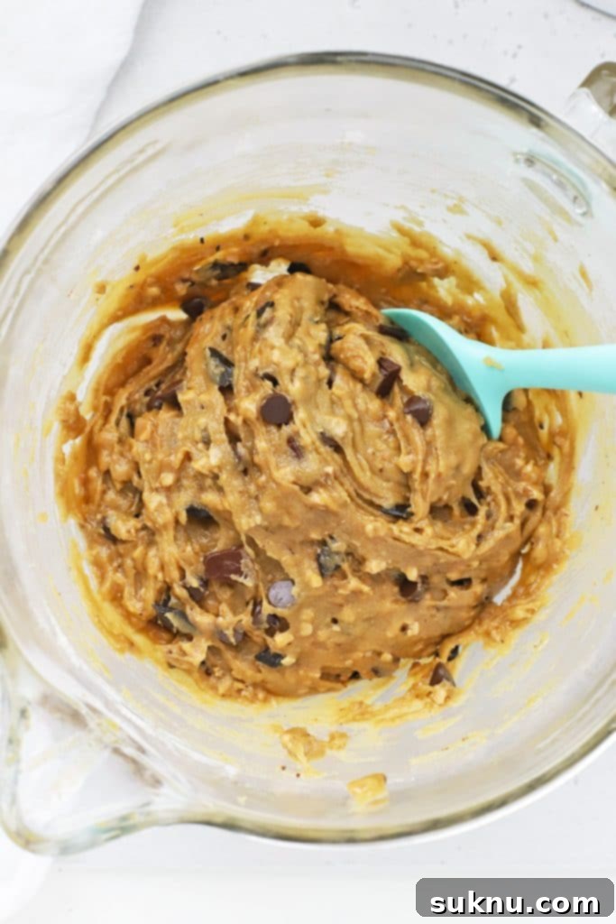 Overhead view of a stand mixer bowl filled with rich, golden brown butter toffee chocolate chip cookie dough