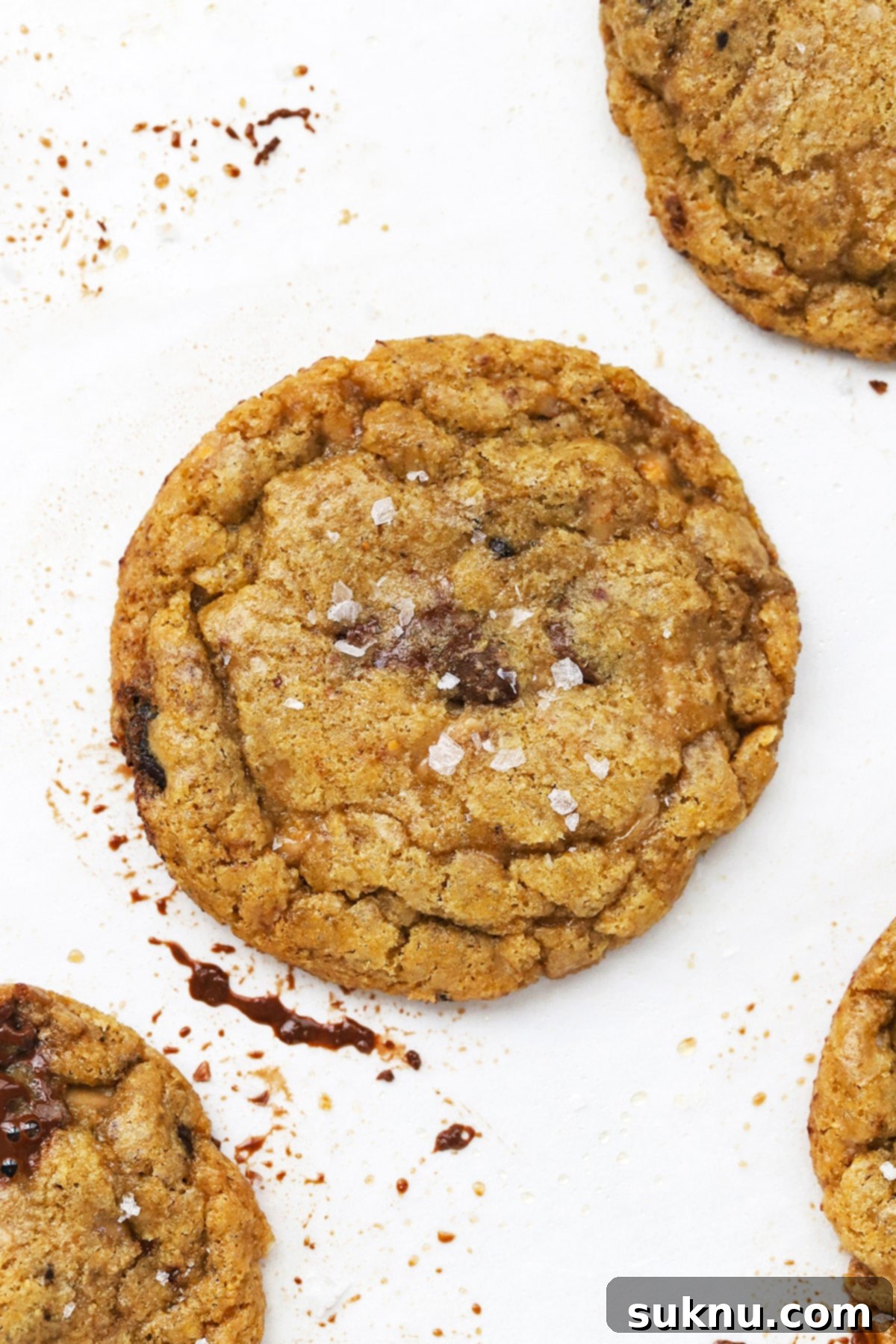 Overhead view of a perfectly golden gluten-free brown butter toffee chocolate chip cookie on a baking sheet, fresh from the oven