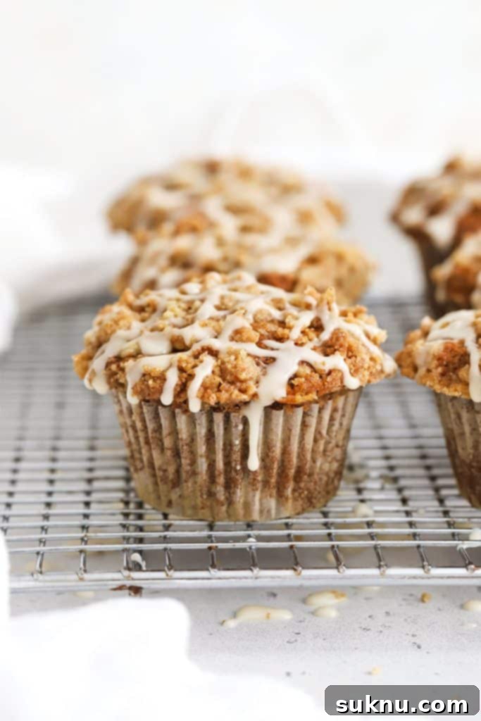 Gluten-Free Banana Crumb Muffin with cinnamon streusel and maple glaze, resting on a wire rack.