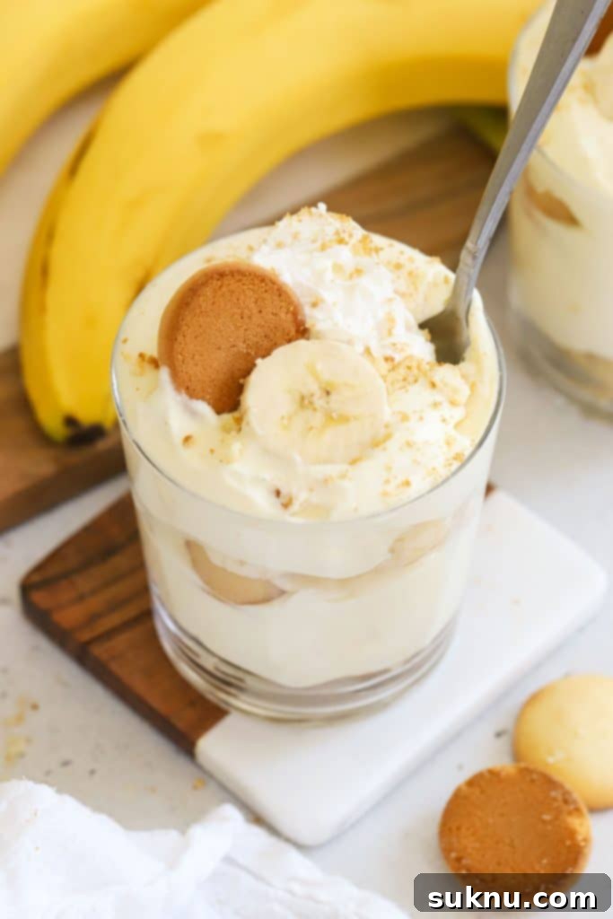 Gluten-free banana pudding served in a small glass bowl, garnished with whipped cream and a wafer.