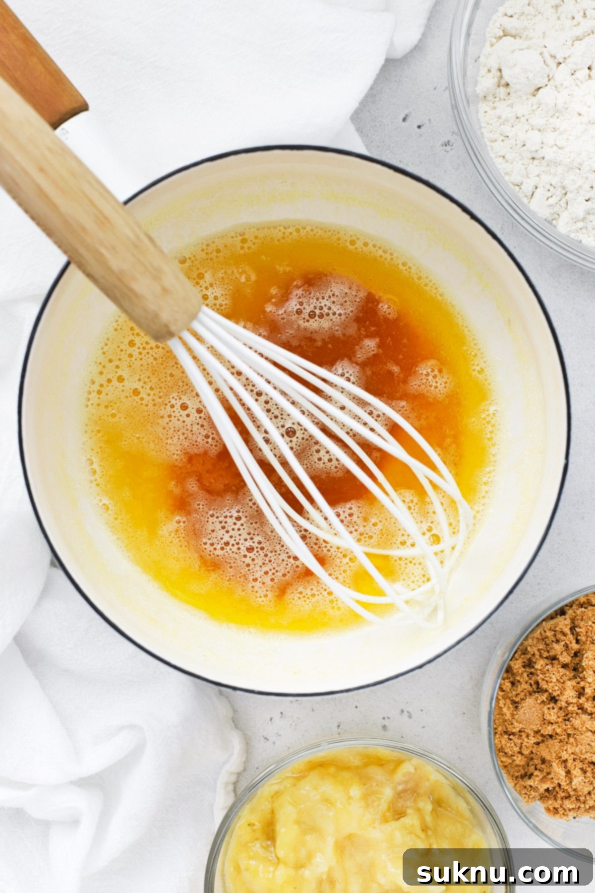 Overhead view of brown butter and key ingredients laid out for making gluten-free brown butter banana bread, including ripe bananas, brown sugar, and flour.