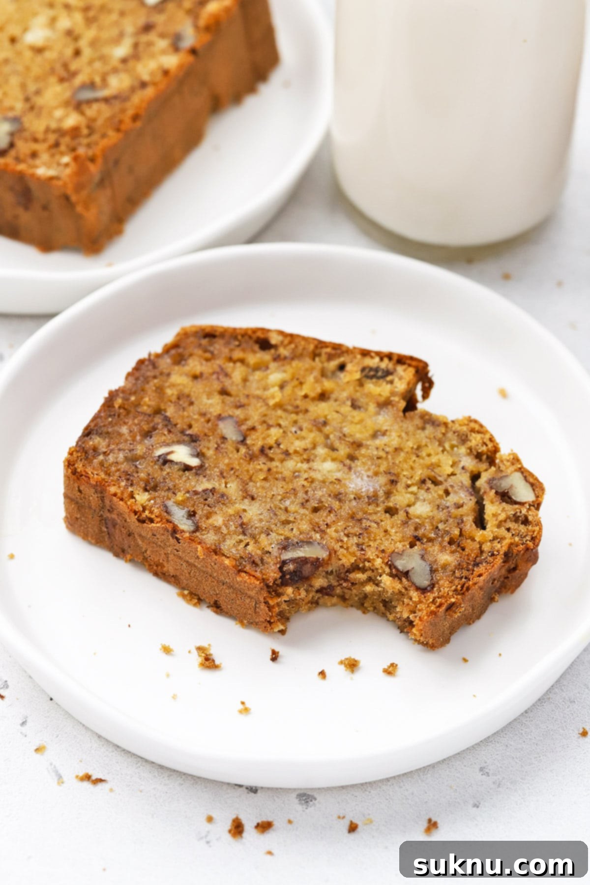 Front view of a slice of gluten-free brown butter banana bread with a bite taken out, showing its tender, moist interior.