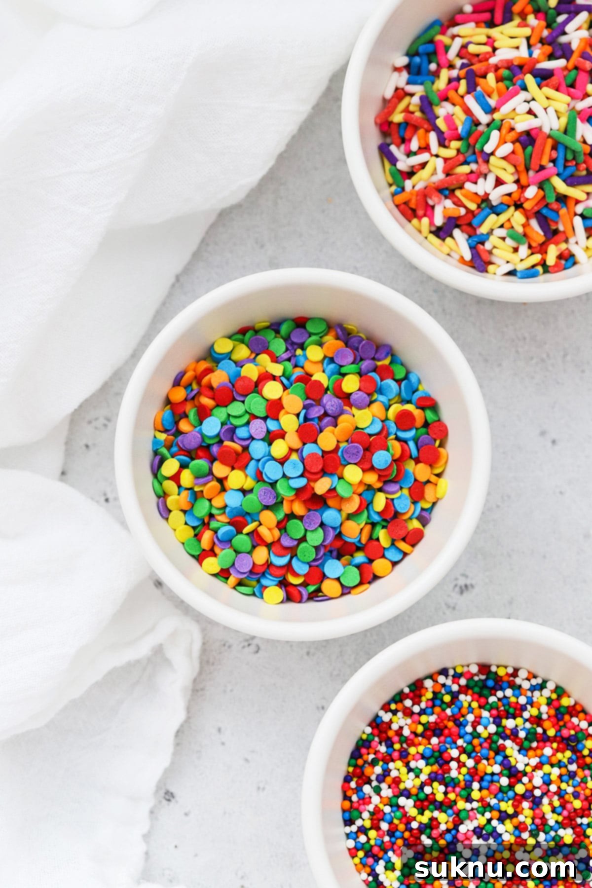 Different kinds of colorful sprinkles in white bowls