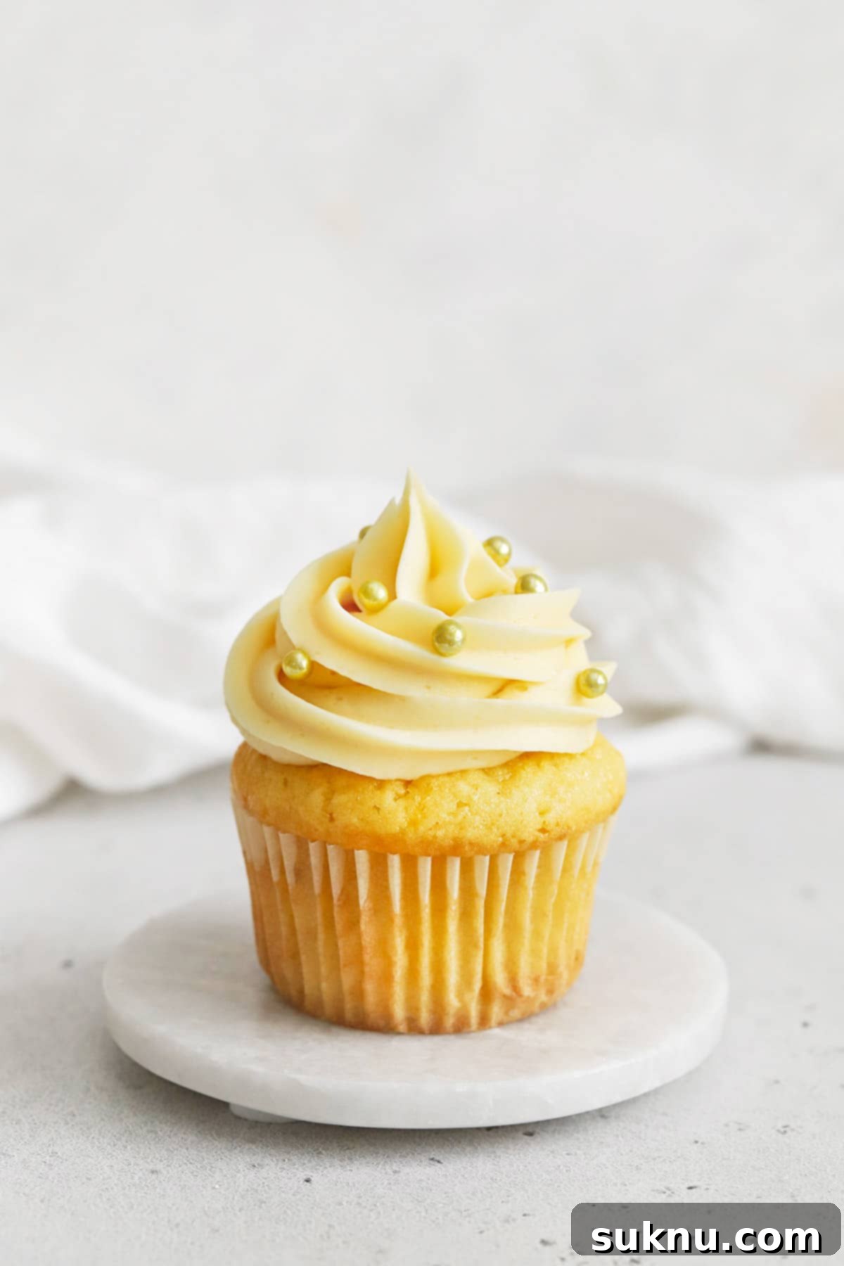gluten-free vanilla cupcake topped with vanilla buttercream and gold dragees sprinkles