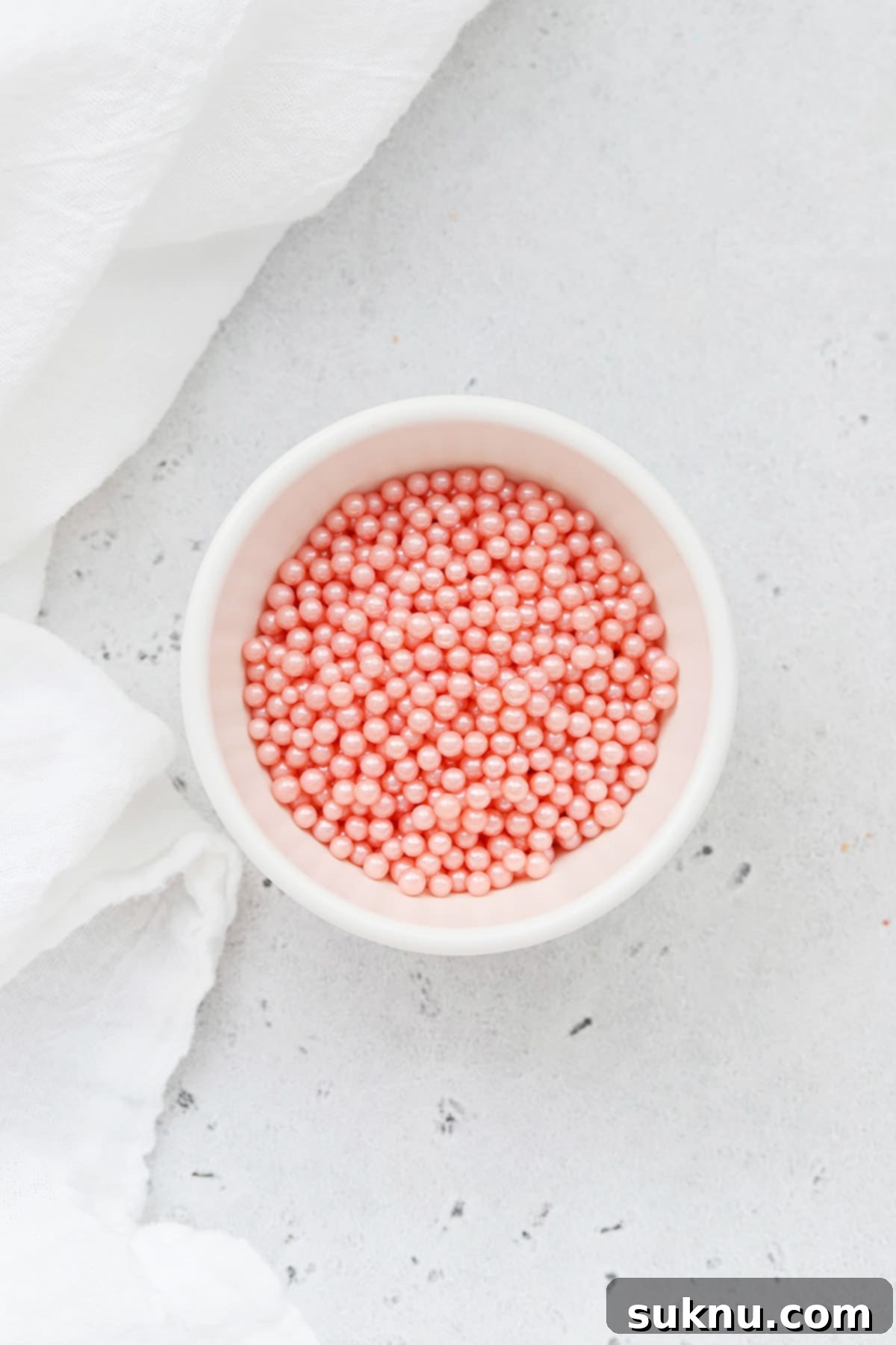 Pink sugar pearls sprinkles in a white bowl