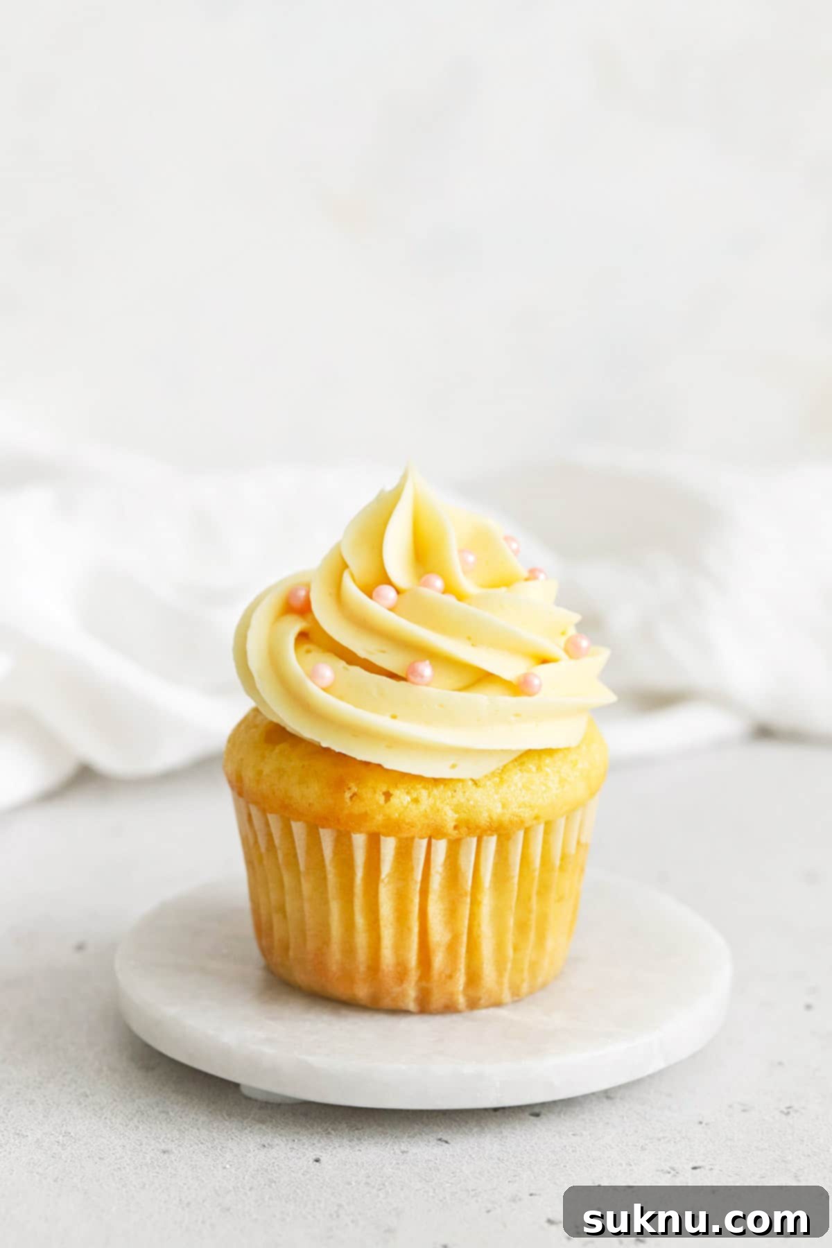gluten-free vanilla cupcake topped with vanilla buttercream and pink sugar pearl sprinkles