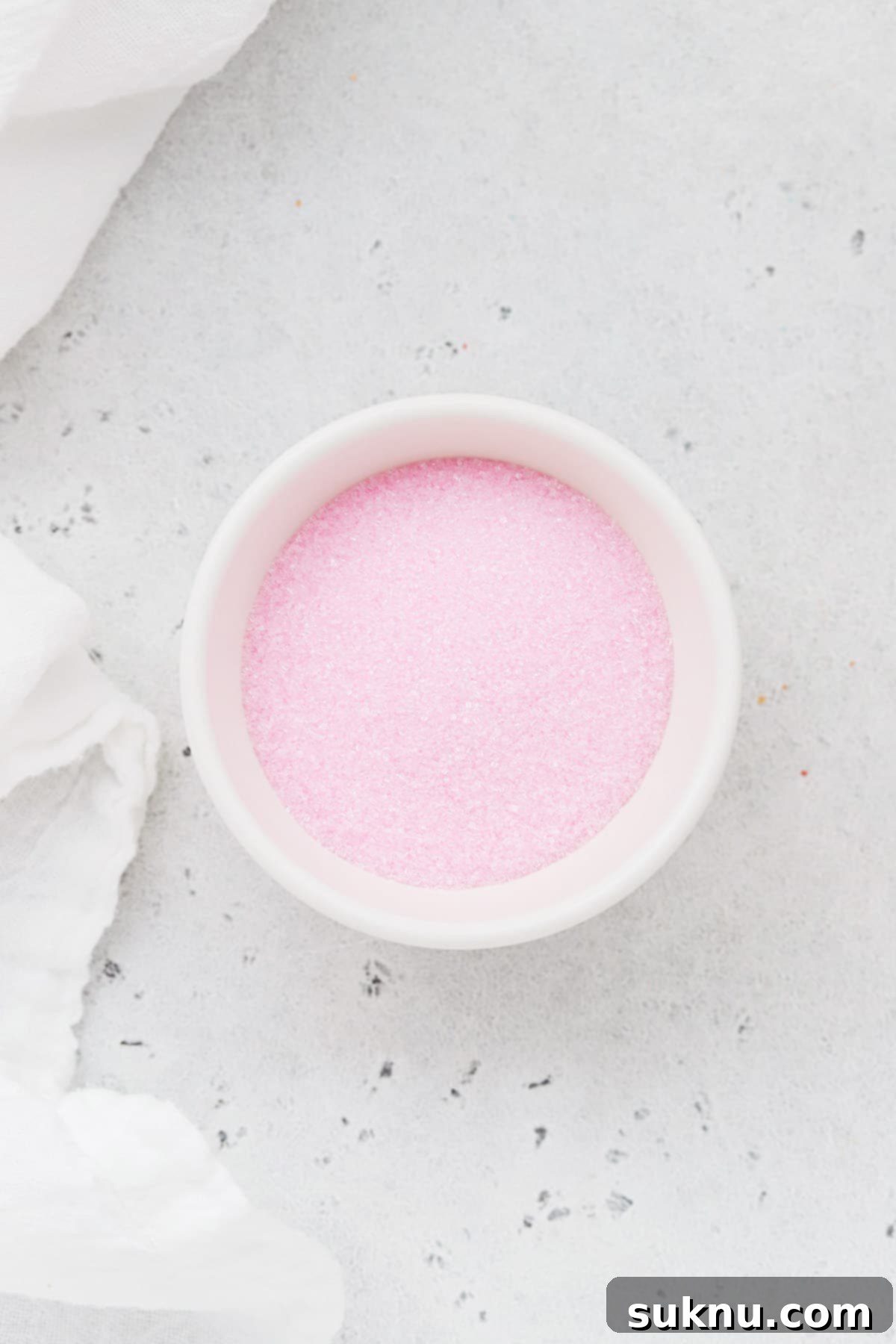 Soft pink sanding sugar sprinkles in a white bowl